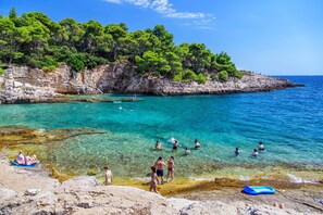 Enjoy swimming and relaxing in the calm turquoise waters, surrounded by lush greenery and gentle waves.