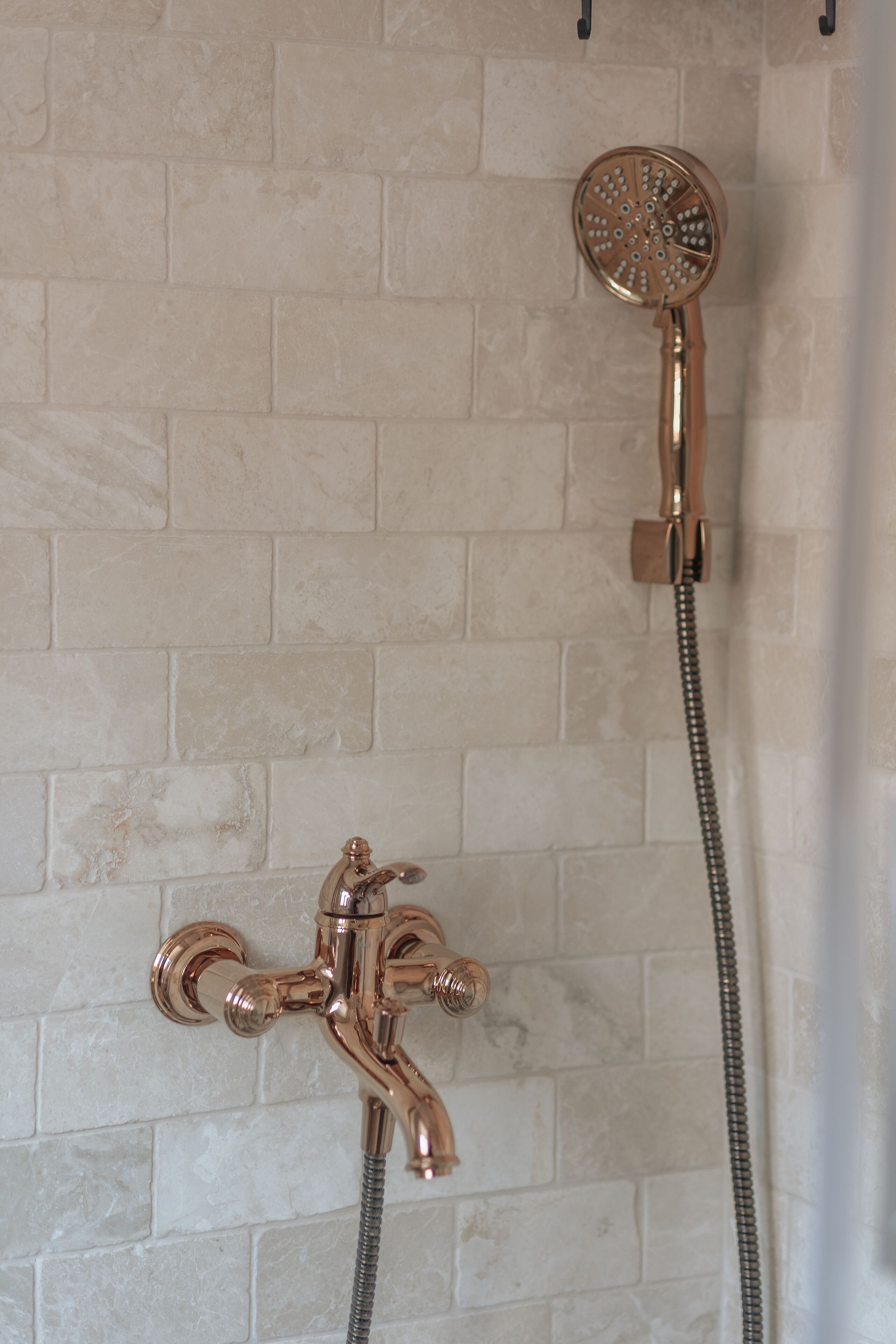 A shower with a handheld showerhead and a wall-mounted faucet.