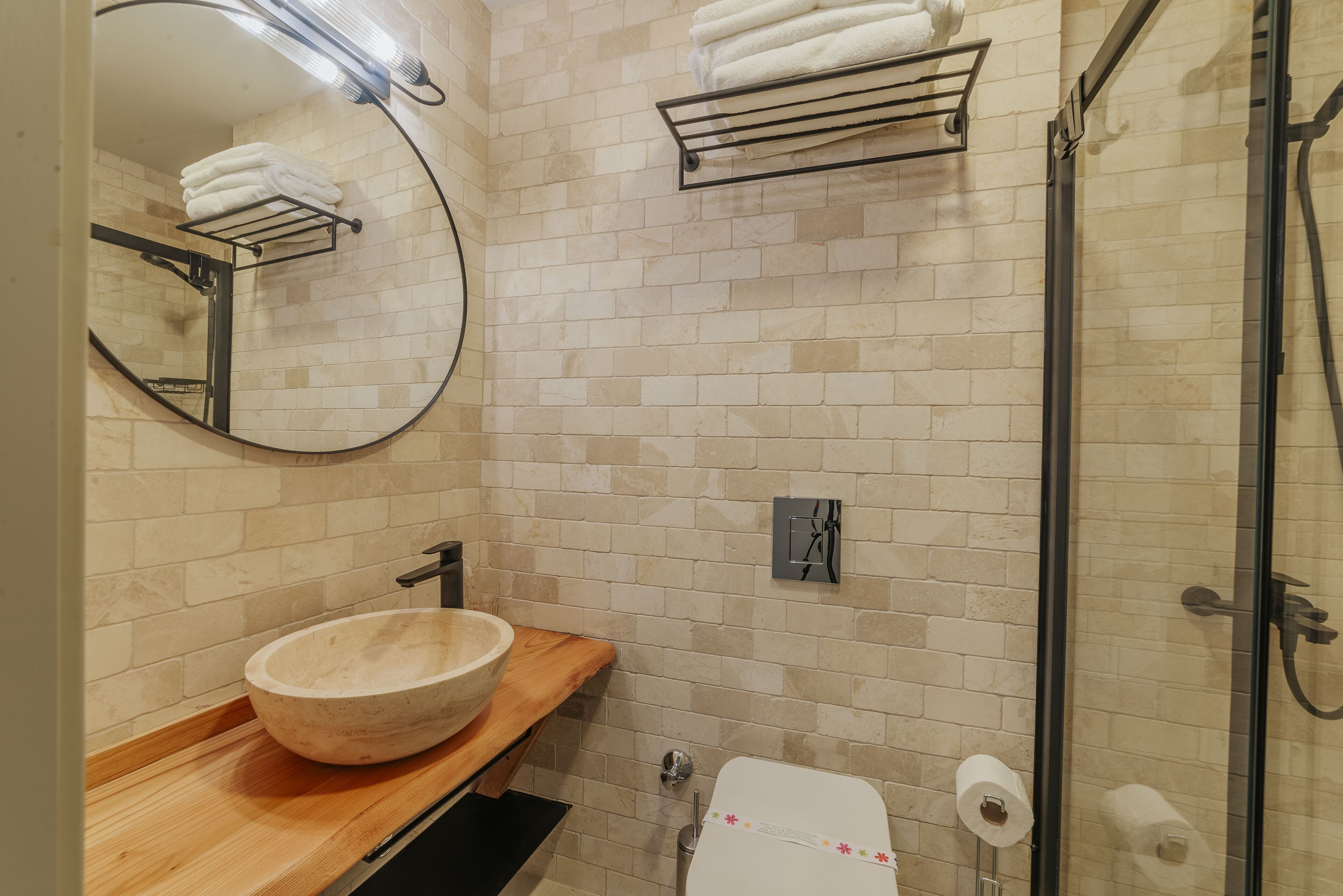 A bathroom with a wooden vanity, a large mirror, a towel rack, and a glass shower enclosure.