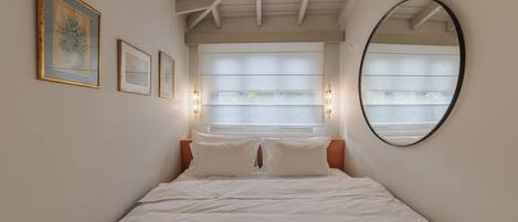 Un dormitorio con una cama, un espejo grande y tres cuadros en la pared.