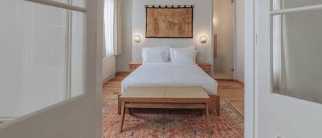 Un dormitorio con una cama, una alfombra grande, un tapiz en la pared y una lámpara de techo.