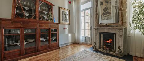 A room with a wooden cabinet, a fireplace, and a large mirror.