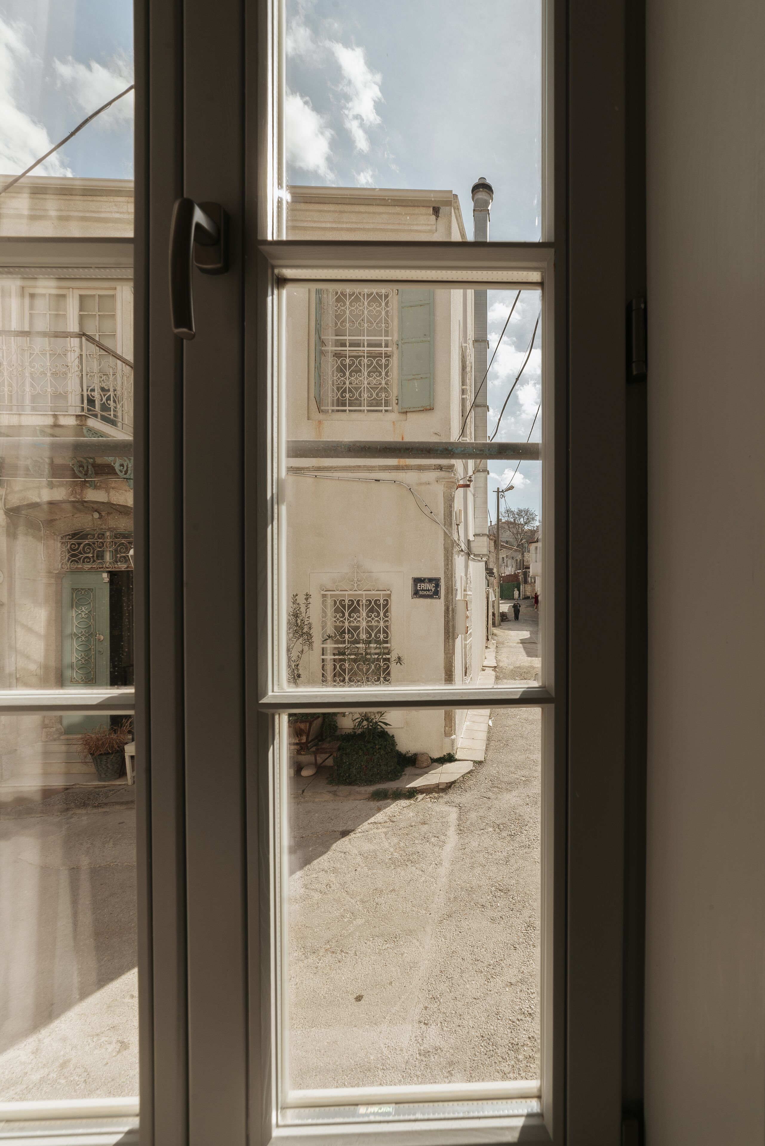 A view through a window with a door, revealing a street with buildings and a sign.