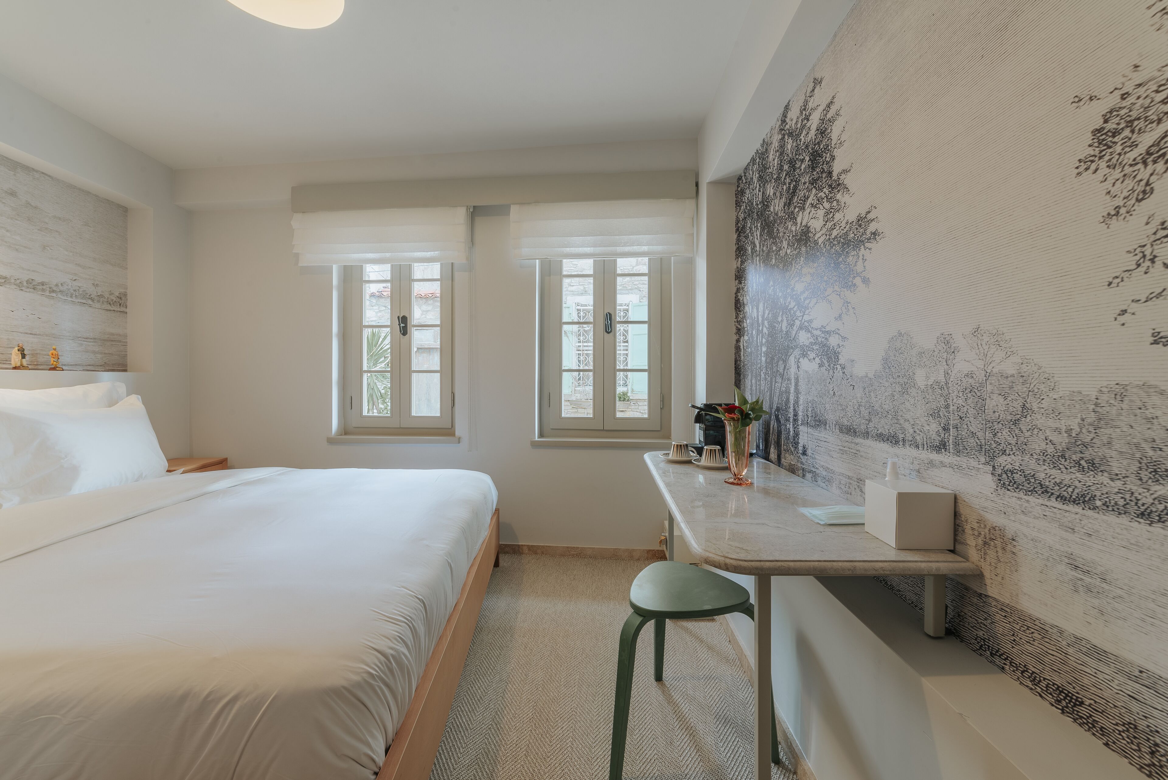 A bedroom with a bed, a desk, and two windows.