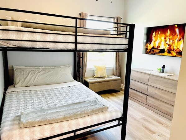 A bunk bed with a lower level bed and a TV mounted on the wall displaying a fire. - Beach House with all Beach Gear + Kayaks Included (Navarre)