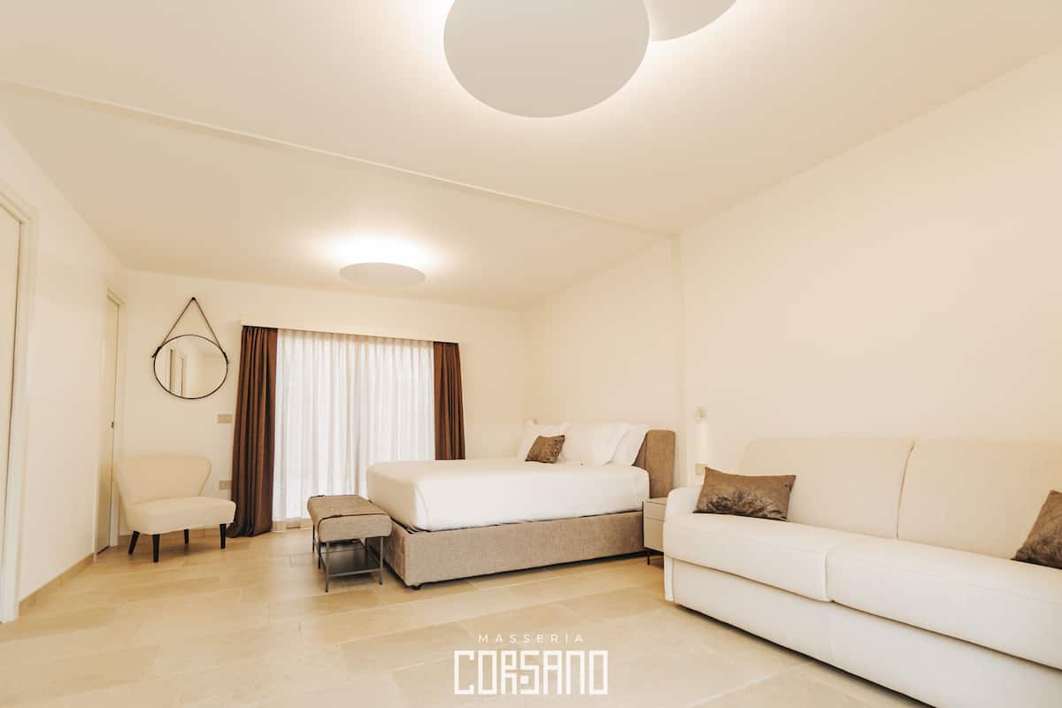 Une chambre d’hôtel moderne, équipée d’un lit, d’un canapé, d’une chaise et d’une petite table.