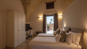 A bedroom with two beds, a desk, and a stone-tiled floor. - Masseria Corsano (Nardò)