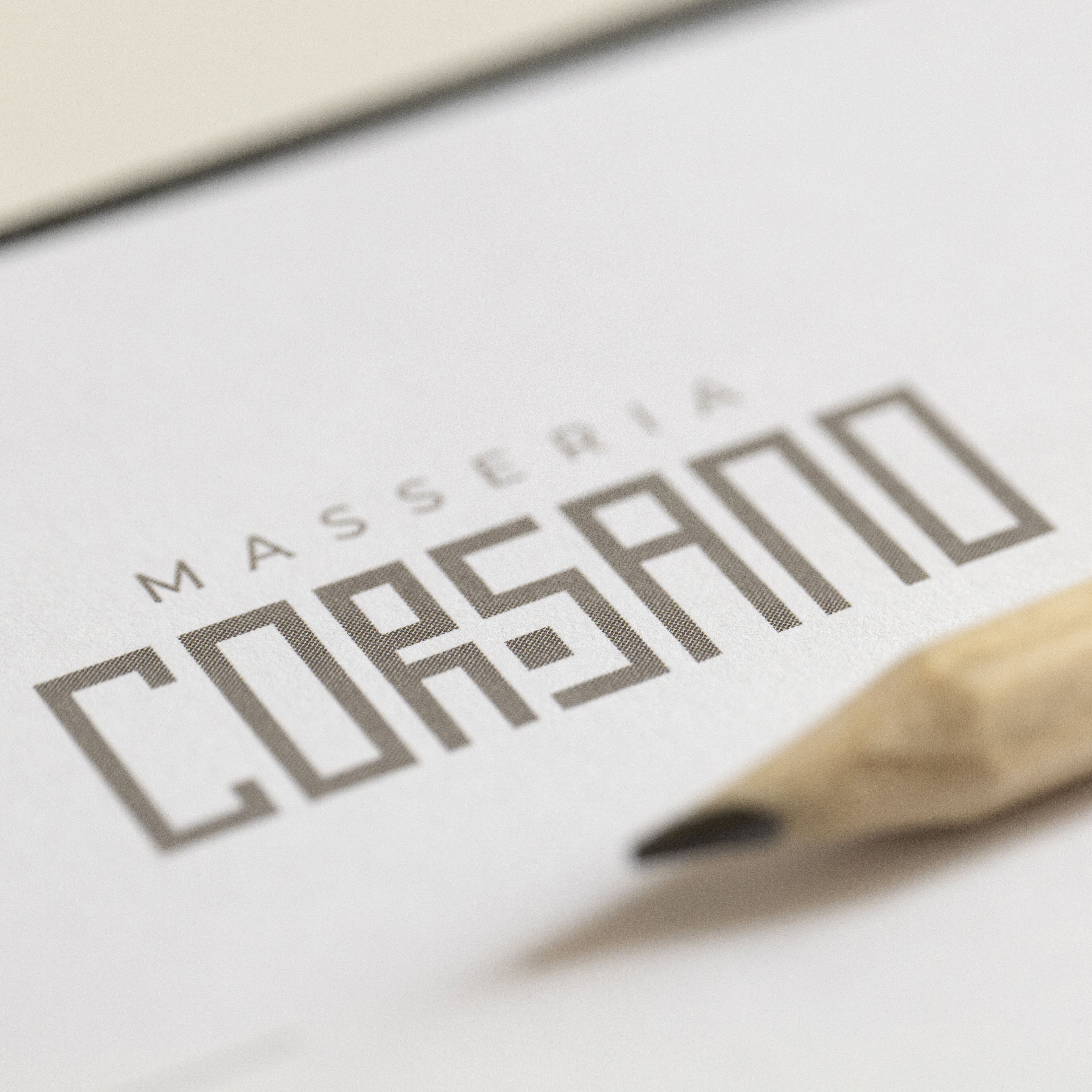 Primer plano de un logotipo con el texto “MASSERIA CORSANO” y un lápiz.