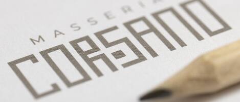 A close-up of a logo with the text "MASSERIA CORSANO" and a pencil.