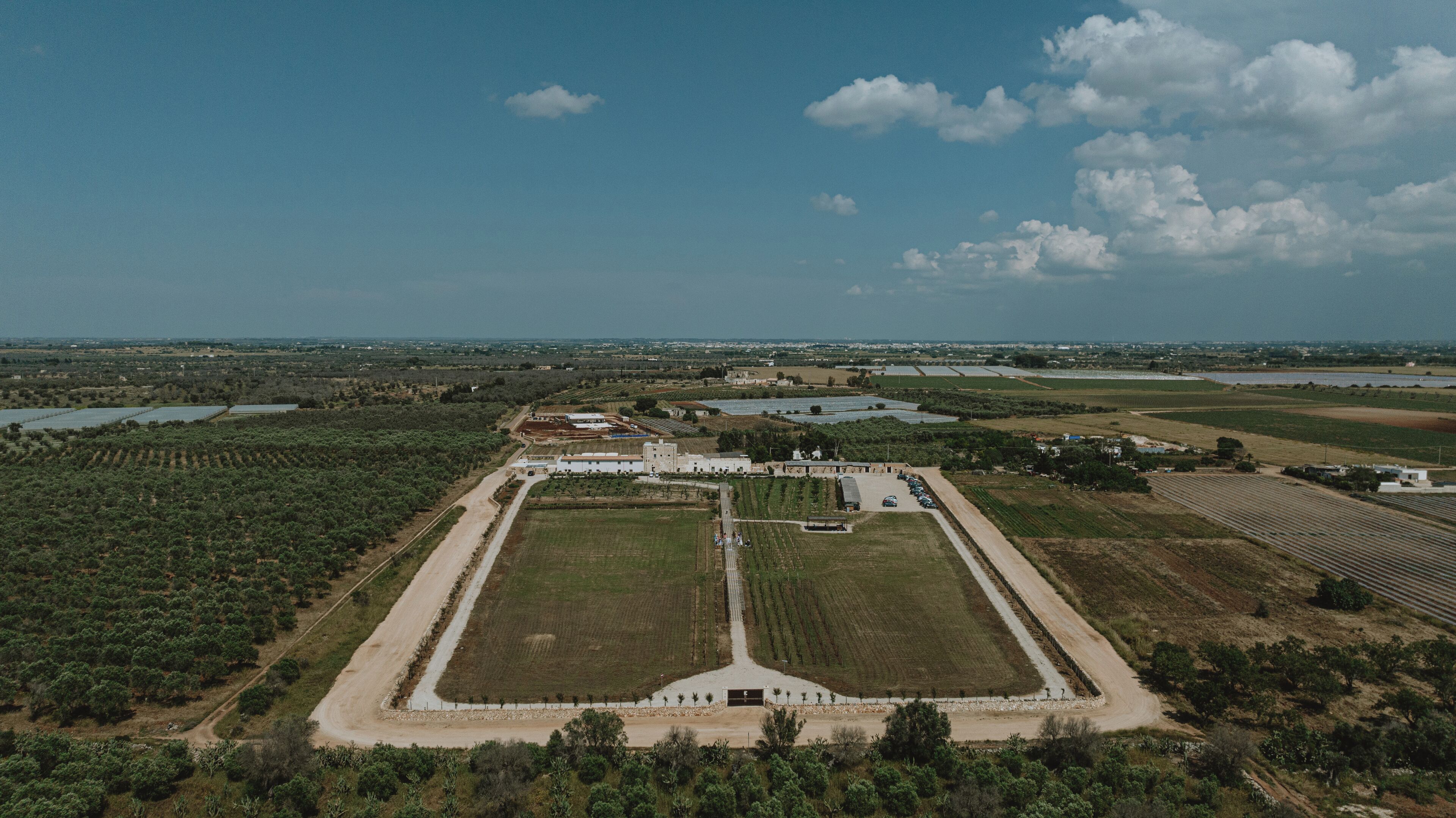 An aerial view of a large, rectangular property with a central building, surrounded by fields and water bodies.