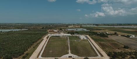 An aerial view of a large, rectangular property with a central building, surrounded by fields and water bodies.
