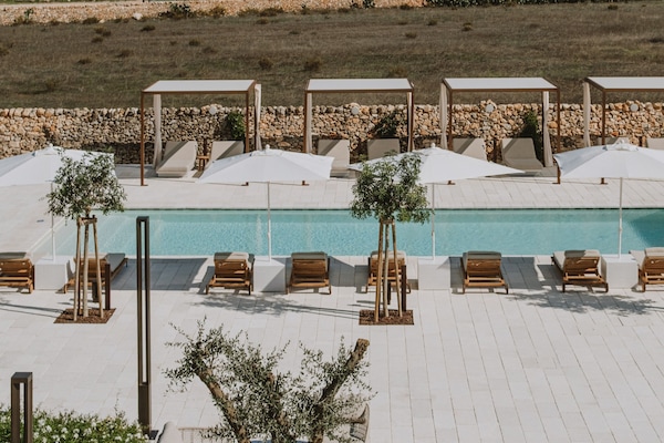 Una piscina al aire libre de temporada, sombrillas, tumbonas