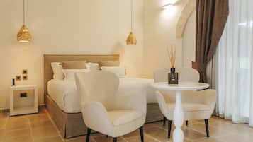 A hotel room with a bed, two chairs, a small table, and two pendant lights.