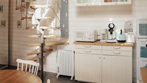 Une cuisine avec des meubles blancs, une table à manger en bois et un four à micro-ondes encastré.