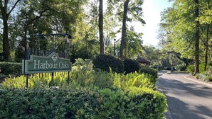 Un letrero que dice 'Harbour Oaks', con abundante follaje y árboles al fondo.