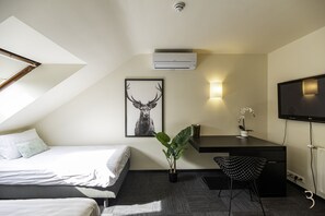 Una habitación de hotel moderna con cama, escritorio, silla y televisor montado.