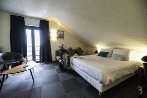 Habitación de hotel con cama, escritorio, silla, bolsa de golf y ventana con cortinas.