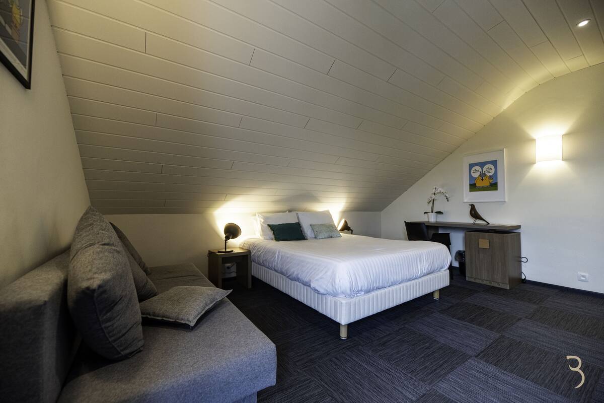 Un dormitorio con cama, mesitas de noche, escritorio y una silla.