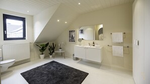 A modern bathroom with a white vanity, a large mirror, a black rug, and a potted plant. - Smart Bnb - Hotel Battice (Herve)