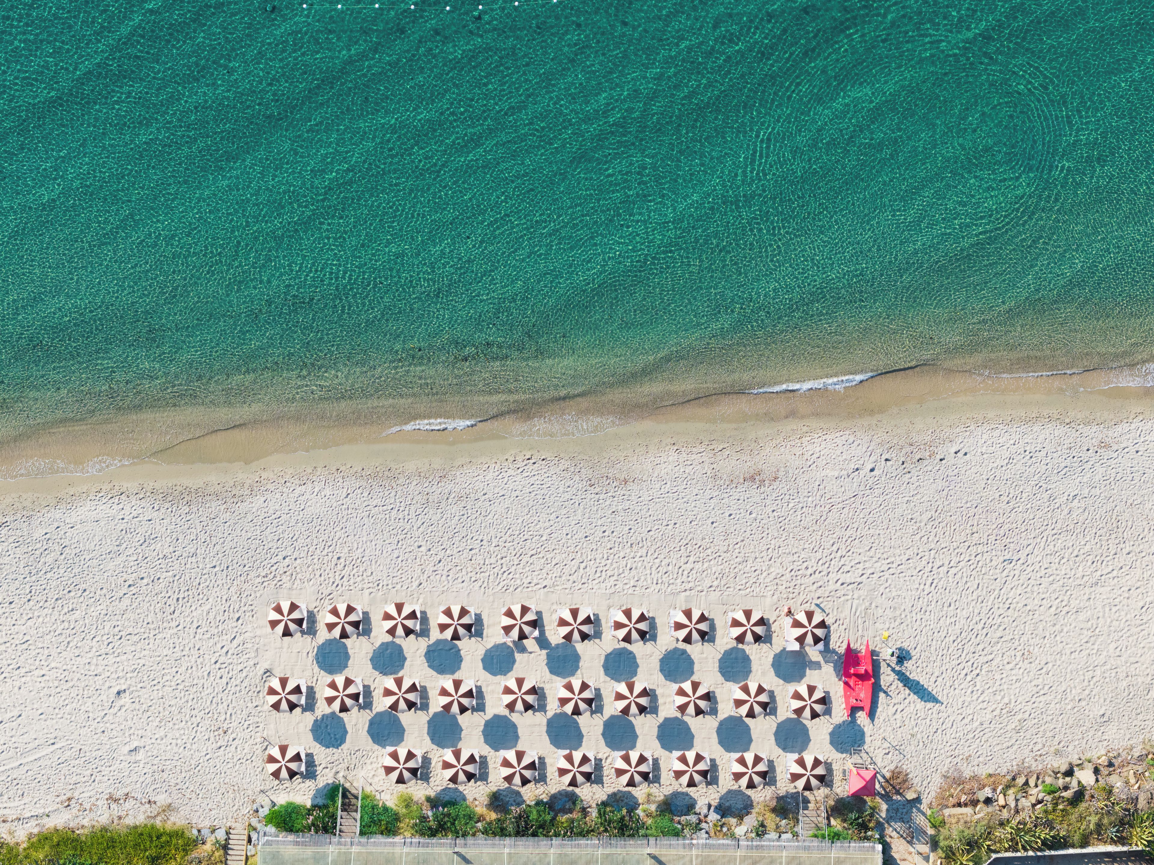 An aerial view of a beach with a patterned umbrella area and a clear view of the ocean.