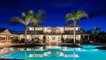 Relax by the resort's spacious pool surrounded by lush greenery and palm trees.
