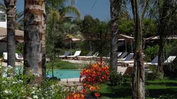 Un resort tropical con palmeras, piscina y sillas de descanso.