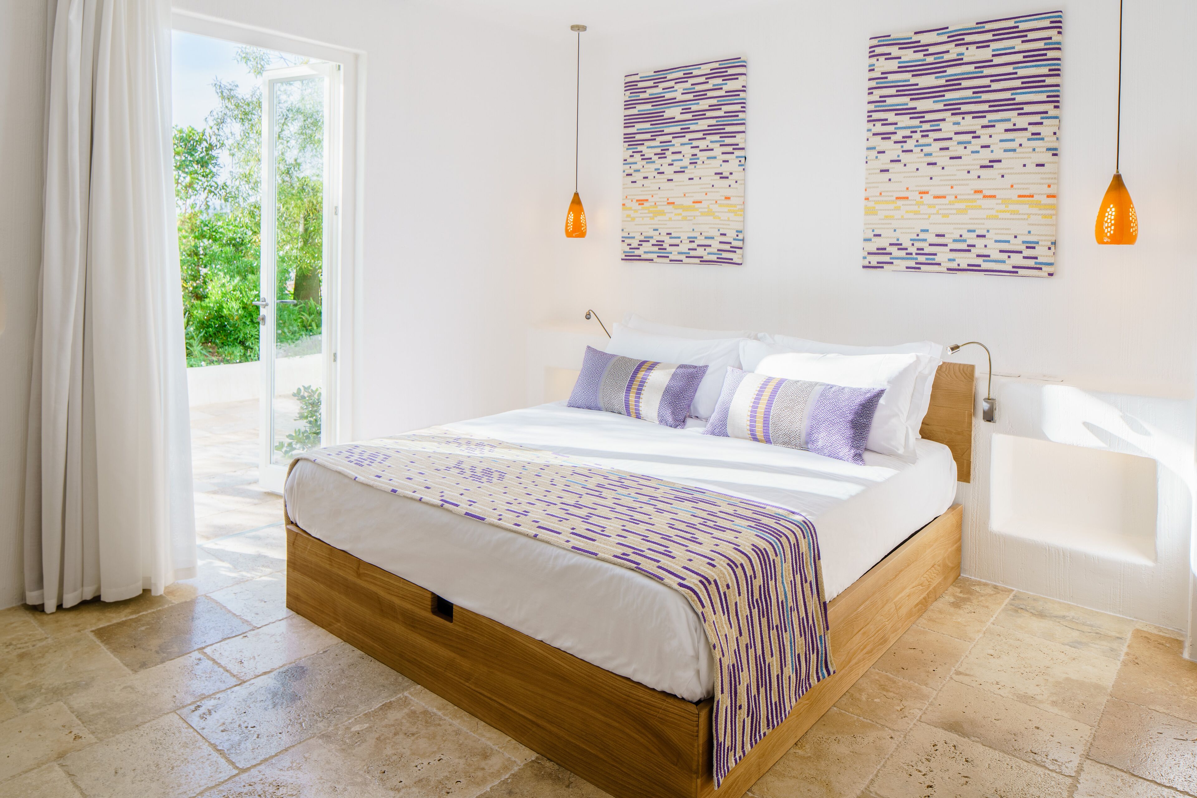 Een slaapkamer met een houten bed, witte beddengoed en twee kunstwerken aan de muur.