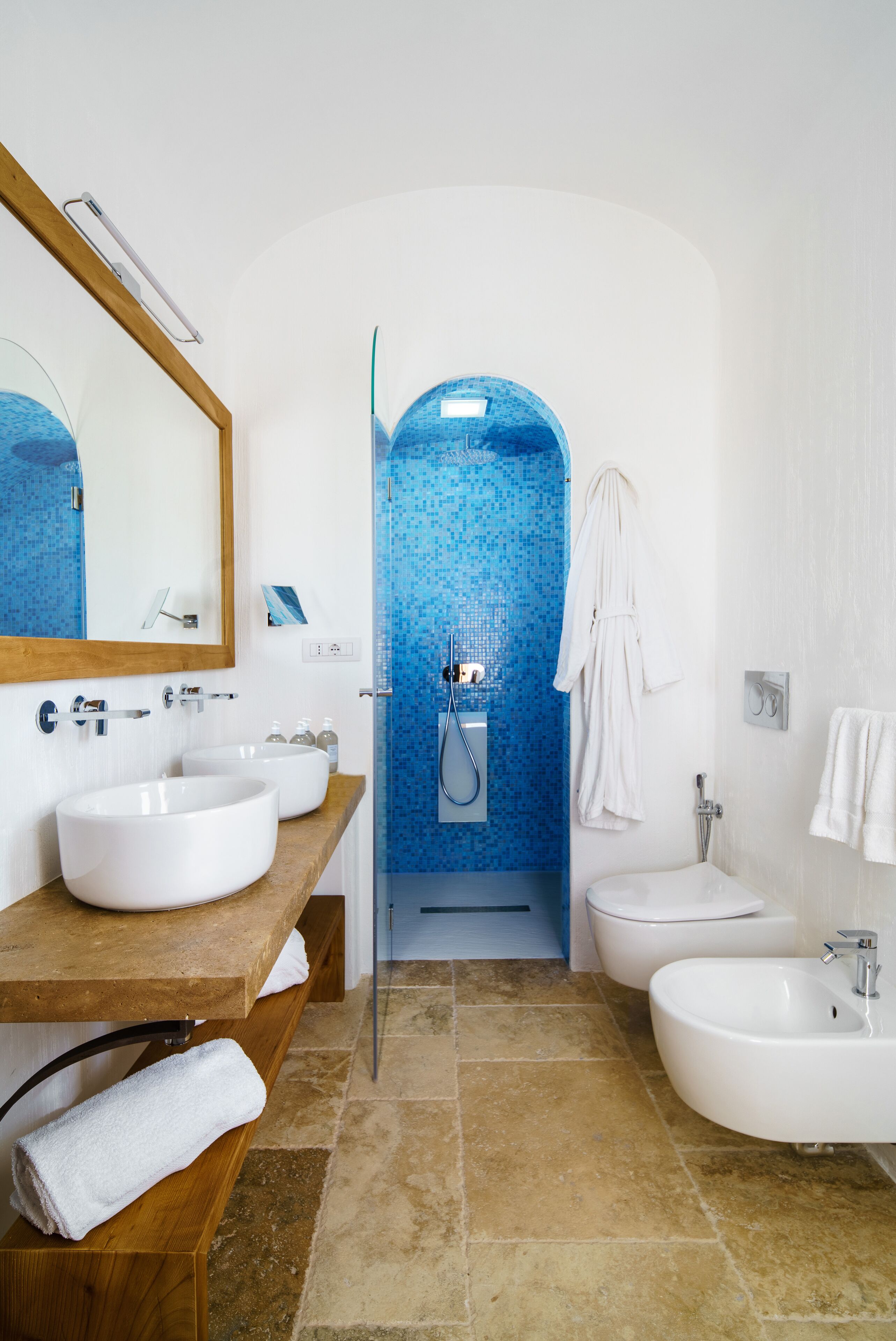 Un bagno con due lavandini, uno specchio, un accappatoio e una zona doccia.