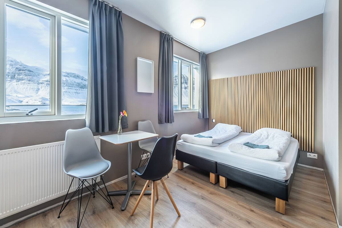 A modern hotel room with a bed, a desk, and a chair.
