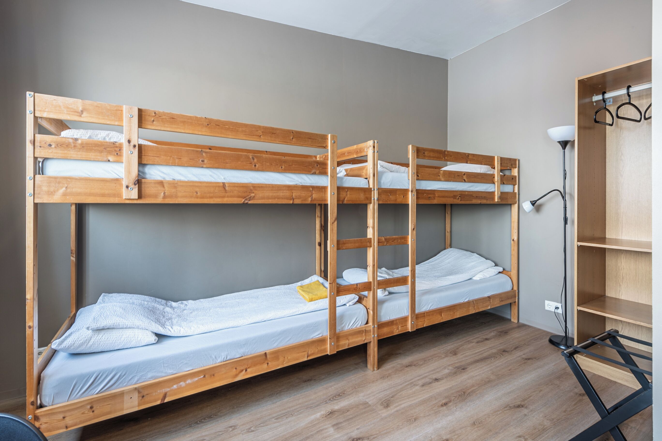 Une chambre avec un lit superposé, un plancher en bois, un bureau et une lampe.