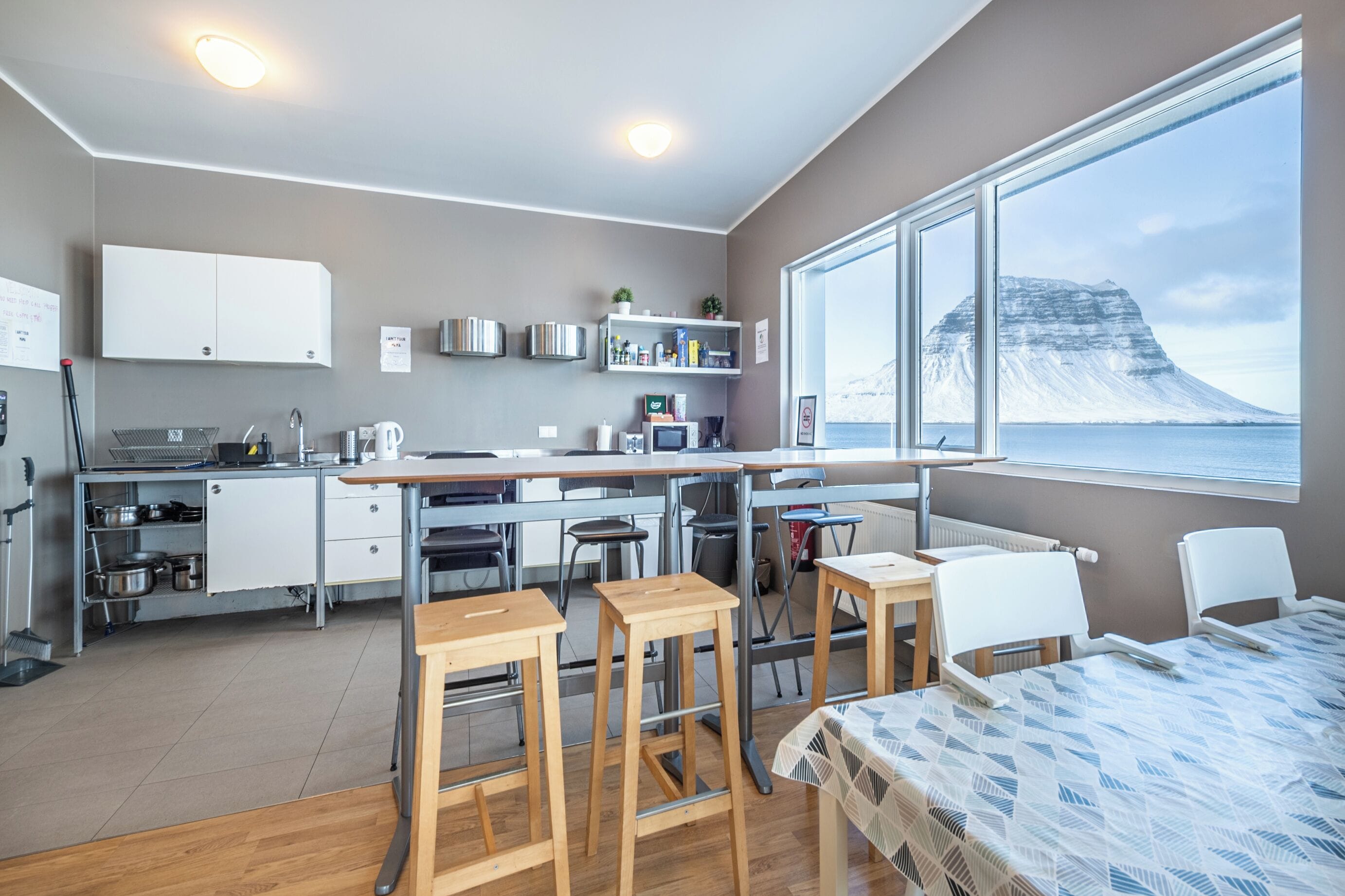 Une cuisine moderne avec une grande fenêtre, des tabourets en bois et une table à manger.