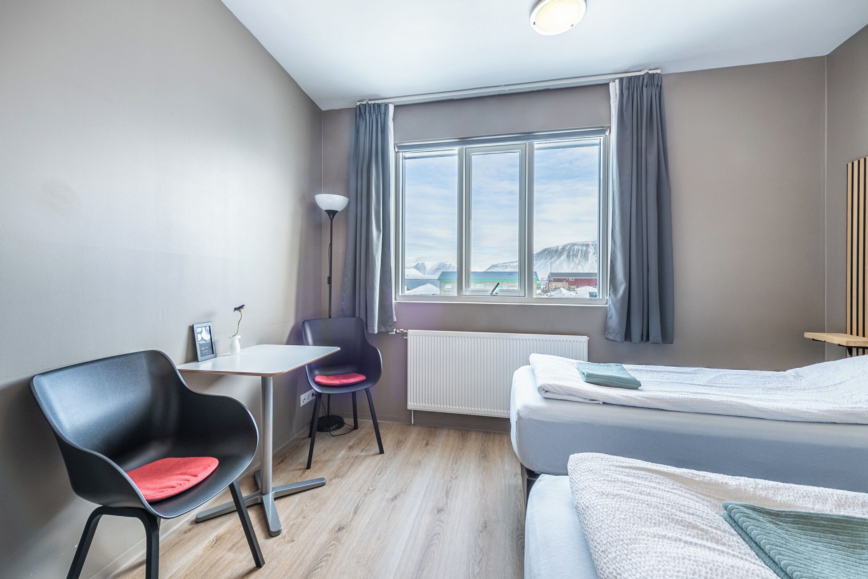 A hotel room with a bed, a desk, a chair, and a window with curtains.
