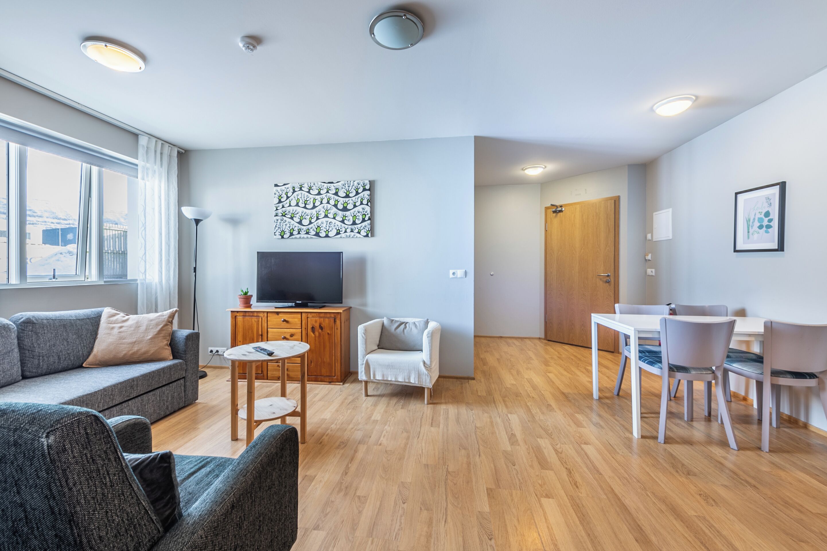 A modern living room with a sofa, TV, and dining area.