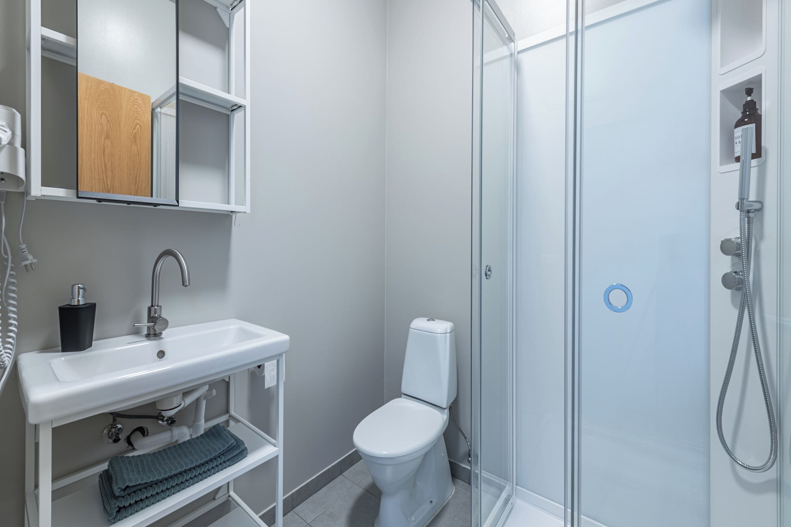 A modern bathroom with a white sink, toilet, and glass shower enclosure.