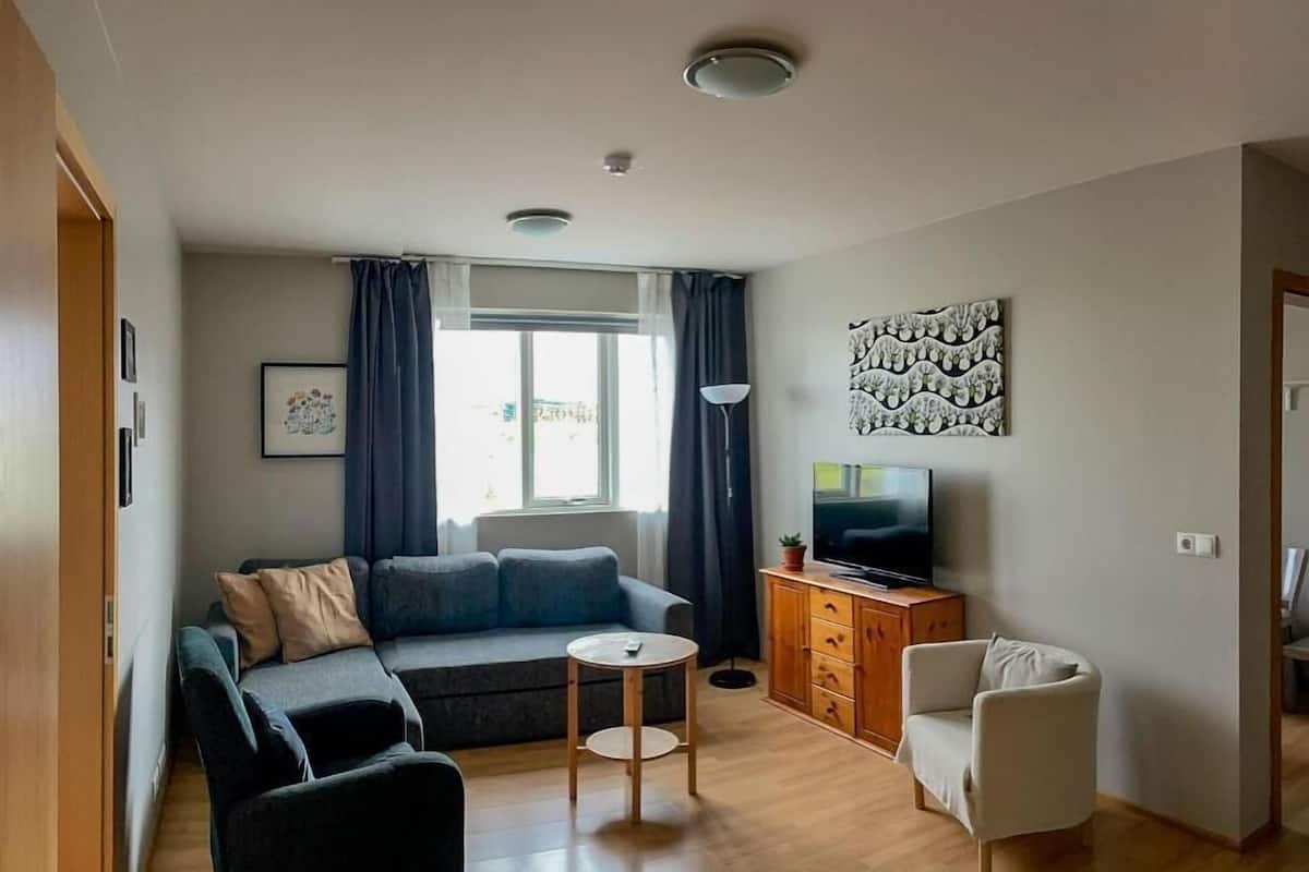 A modern living room with a sofa, armchair, TV, and a small table.