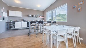 Una cocina moderna con armarios blancos, un comedor con mesa y sillas, y un amplio ventanal con vistas a la montaña.