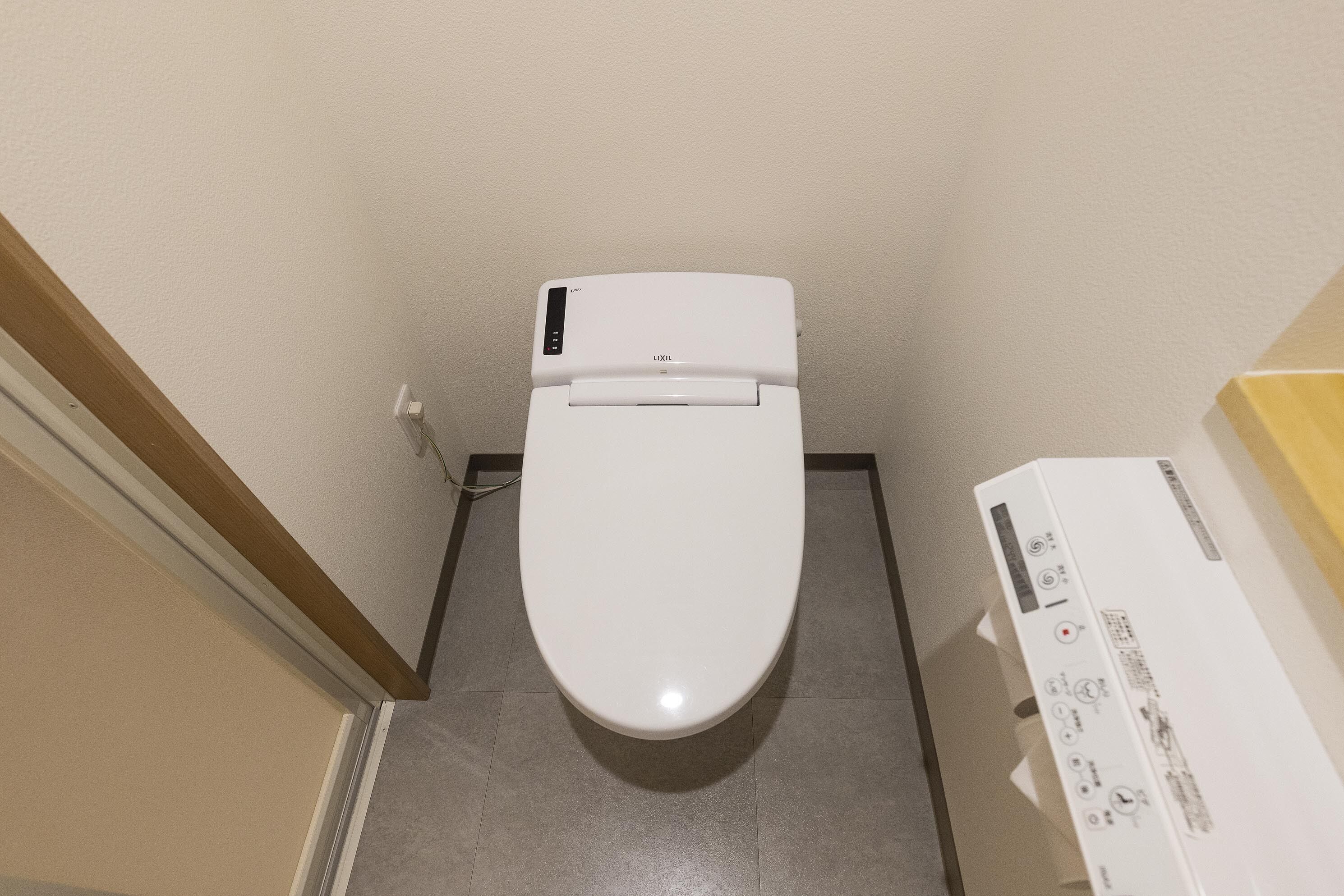 A white toilet in a bathroom with a control panel on the right.