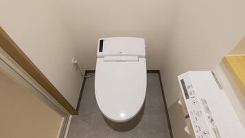 A white toilet in a bathroom with a control panel on the right.