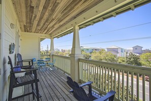 A wooden deck with chairs and a table, overlooking a residential area with houses and trees.