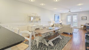 A spacious room with a dining area, a white bookshelf, and a ceiling fan. - Grand Isle 302 - Community Pool, Private Beach Access, 30A, Near Seaside! (Seagrove Beach)