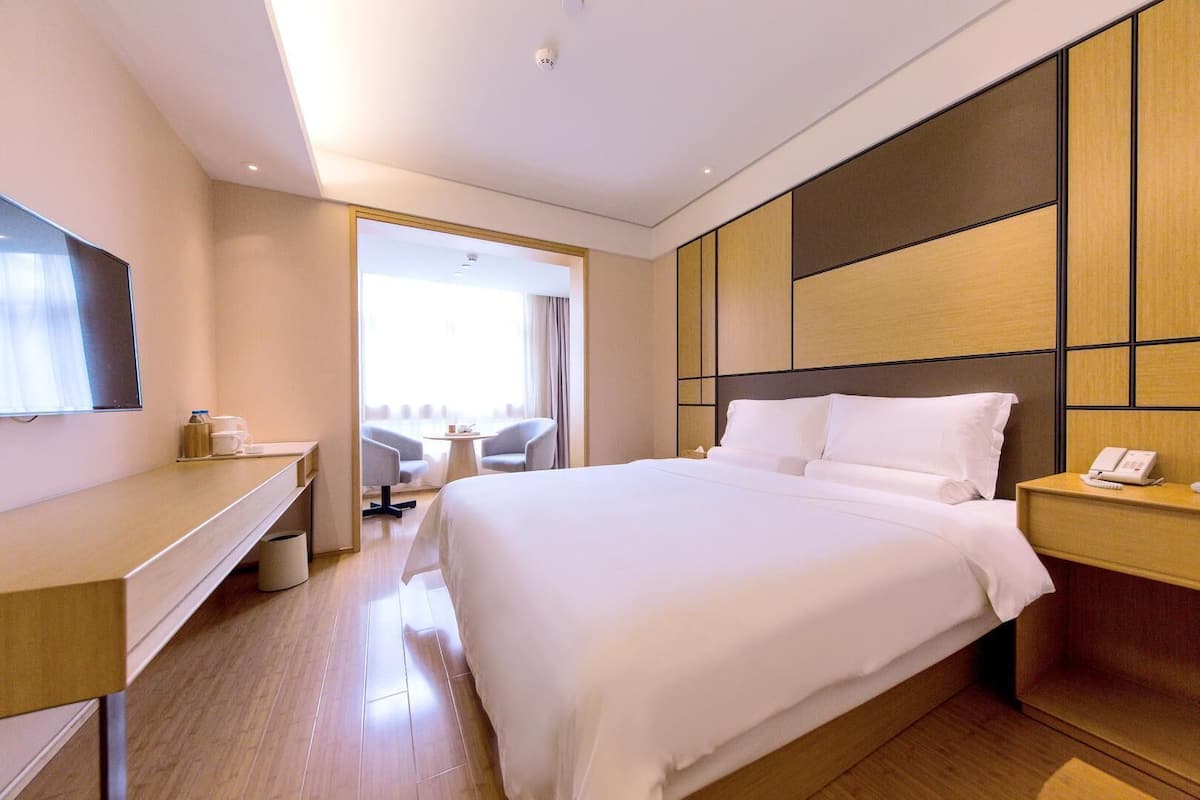 Une chambre d’hôtel avec un grand lit, un bureau, une chaise, une télévision et une vue sur l’extérieur.