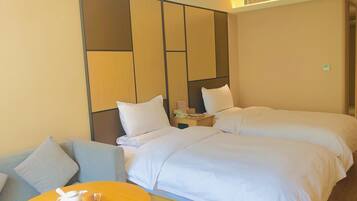 A hotel room with two beds, a sofa, a small round table with a teapot, and a wall panel design.