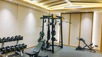 A gym with a bench press, dumbbells, a squat rack, and a bench press machine.