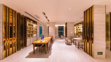 Un interior moderno con una larga mesa de madera, sillas y estanterías.