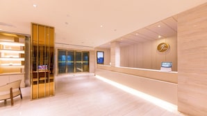 A hotel reception area with a modern design, featuring a reception desk, a seating area, and a glass door entrance. - Ji Hotel (xi'an Giant Wild Goose Pagoda East Xiaoz (Xi'an)