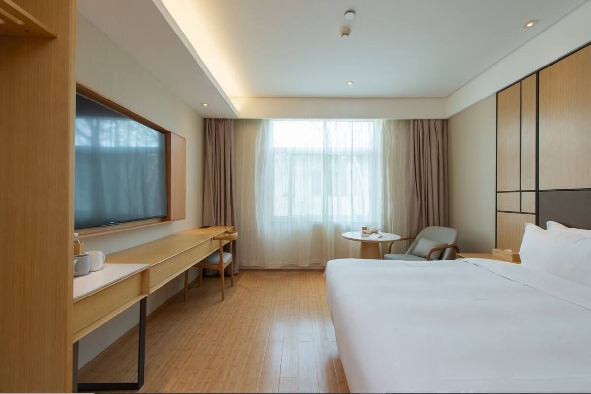 Une chambre d’hôtel équipée d’un lit, d’un bureau, d’une chaise, d’une télévision et d’une fenêtre avec des rideaux.