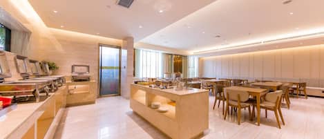 A modern hotel dining area with a central island, seating arrangements, and a view through a glass door.