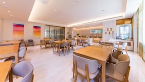 A modern dining area with multiple tables and chairs, a kitchen in the background, and large windows. - Ji Hotel (xi'an Giant Wild Goose Pagoda East Xiaoz (Xi'an)