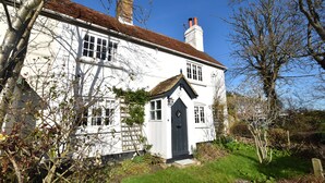 A white house with a black door, a small porch, and a chimney.