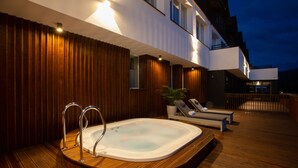 An outdoor hot tub area with wooden decking, lounge chairs, and a potted plant. - Hotel Beskid Balneo Medical Resort & SPA (Piwniczna-Zdroj)